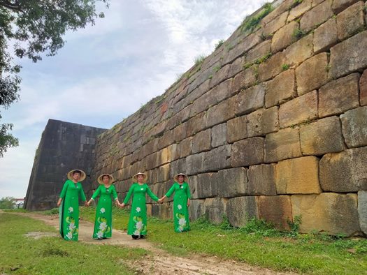Giữa không gian cổ kính của Thành Nhà Hồ, đoàn khách du lịch trong tà áo dài xanh tạo nên bức tranh giao thoa giữa quá khứ và hiện tại
